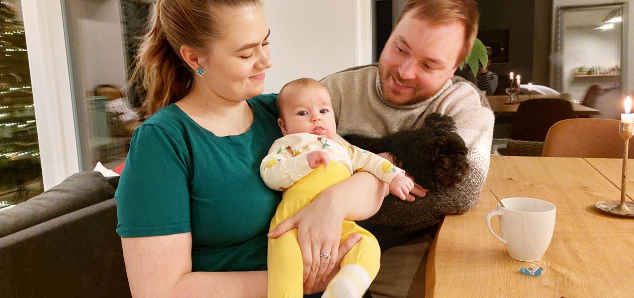 vanhemmat ja pieni lapsi kotona keittiönpöydän ääressä