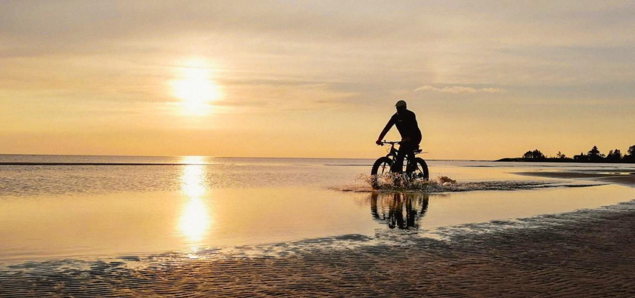 Pyöräilijä merenrannalla auringonlaskussa